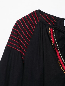 Détail de la broderie froncée et des coutures ondulées colorées sur une robe noire longue