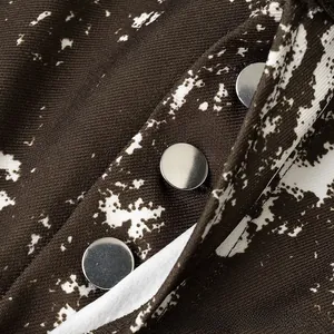 Makro-Detail des braunen Twill-Stoffs mit silbernen Knöpfen und weißem Marmor-Druckmuster