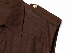Close-up of brown linen vest shoulder strap featuring a vintage gold metal button detail