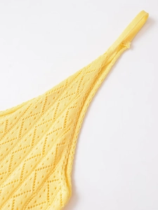 Détail d'un caraco en tricot jaune avec des motifs de losanges ajourés au crochet