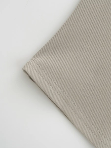 Detailed macro view of beige ribbed knit fabric with neat double-stitch hem finishing