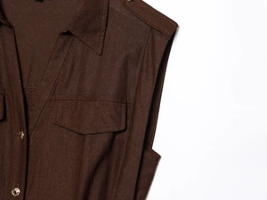 Detailed view of dark brown linen vest with gold buttons and flap pockets detail