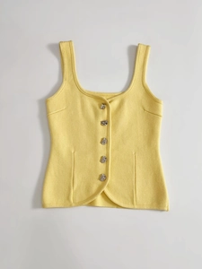 Detailed macro view of yellow knit vest with unique silver irregular metal buttons