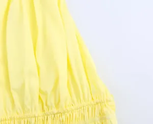 Detailed close-up of yellow fabric with elastic smocking and refined pleated texture