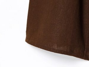 Macro detail of dark brown linen midi dress fabric showing natural texture and fine stitching