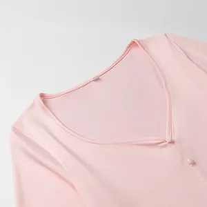 Détail de la robe en maille rose clair avec col en V, tissu délicat et boutons en tissu