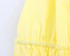 Detail view of the yellow halter top featuring elastic ruched fabric and pleat design