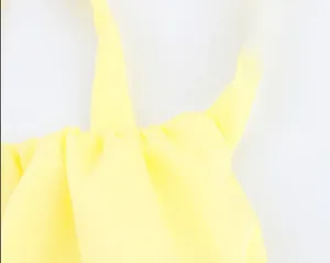Detailed close-up of bright yellow halter neck top with gathered pleats and thin straps