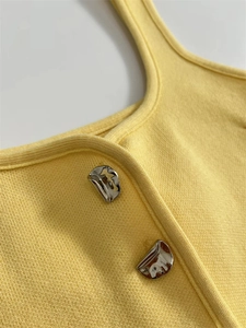 Close-up of light yellow knit top with unique silver irregular metal buttons