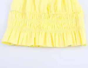 Detailed view of yellow smocking fabric with delicate ruffle hem and woven texture