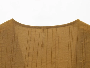 Detailed macro view of the pleated fabric texture and round neckline of the tan two-piece set