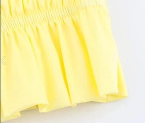 Detail of smocked bright yellow fabric with elastic stitching and ruffled hem finish