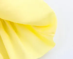 Macro close-up showing the smooth yellow fabric texture and neat sewing stitch details