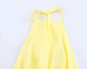 Detail of light yellow halter top featuring a neck tie bow and lightweight fabric texture