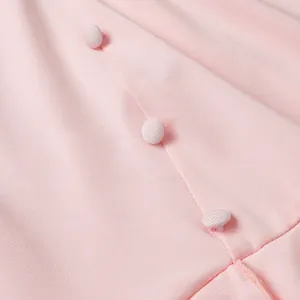 Gros plan de trois boutons recouverts de tissu rose sur un détail de tricot côtelé fin