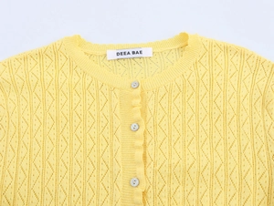Detailed macro view of yellow hollow-out knit cardigan with textured diamond patterns