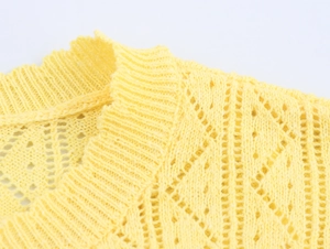 Detailed close-up of bright yellow knit sweater with hollow pattern and ribbed neckline
