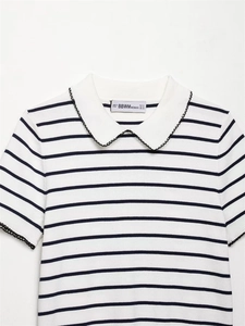 Detail of white polo collar with black scalloped trim on striped knit sweater