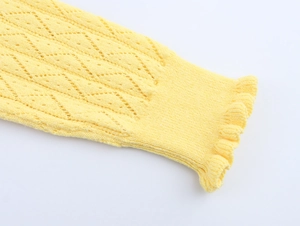Close-up of yellow knit fabric with hollow patterns and ruffled edges detail