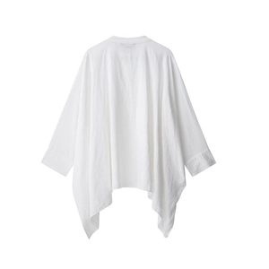 Dettaglio dell'orlo asimmetrico e della trama di una camicia a poncho in lino bianco