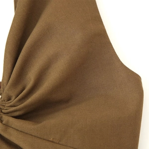 Macro view of brown linen blend fabric showing detailed weave texture and pleats