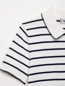 Detailed view of striped knit polo with black wavy lace trim on the collar and cuffs