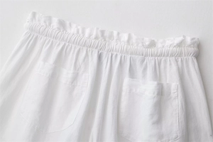 Dettaglio degli shorts in lino bianco con vita elastica arricciata e tasche posteriori