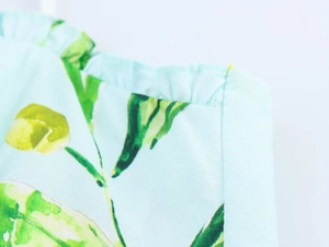 Detail of lemon print cotton dress featuring delicate pleated edges and thin straps