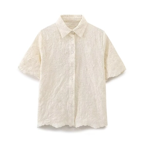 Détail de chemise blanche à manches courtes avec broderie florale et finitions ajourées