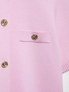 Détail de veste en maille rose avec boutons dorés gaufrés et texture côtelée