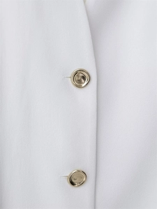 Detailed macro view of gold metal buttons on premium white tailored jacket fabric