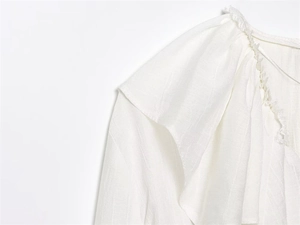 Detailed macro view of layered ruffles and frayed edges on a white woven shirt