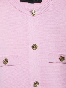 Détail du cardigan en maille rose avec des boutons dorés texturés et poche décorative