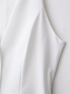Detailed macro shot of white textured fabric and premium stitching on a sleeveless dress