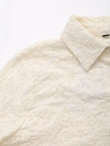 Vue détaillée d'une chemise crème avec broderies florales complexes et col classique