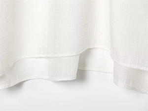 Detail of white layered hemline showing vertical crinkle texture and fine stitching