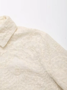 Détail du col rabattu et broderie florale sur un chemisier en coton et lin beige