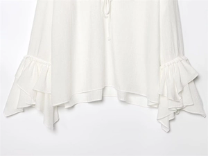 Close-up of white chiffon blouse showing tiered ruffle cuffs and delicate fabric texture
