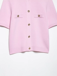 Gros plan sur le cardigan en maille rose avec boutons dorés gaufrés et texture de qualité