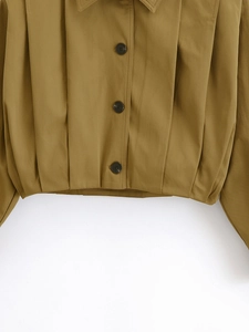 Detailed view of khaki cropped jacket with vertical pleated texture and button closure