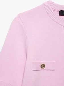 Détail du haut en maille gaufrée rose clair avec un élégant bouton doré à motif en relief