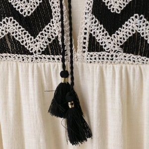 Bohemian V-neck dress with intricate black geometric embroidery and tassel drawstring ties