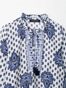 Close-up of bohemian paisley print on white fabric with tassel tie and ruffled collar
