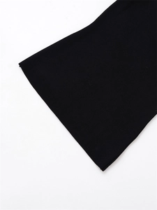 Close-up of black ribbed knit fabric showing the detailed texture and flared sleeve cuff