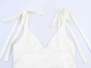 Detail of ivory satin camisole featuring a deep V-neck and elegant ribbon bow straps