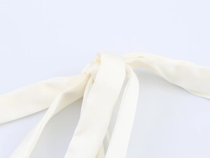 Close-up of cream white satin ribbon straps featuring a soft silky texture and elegant knot