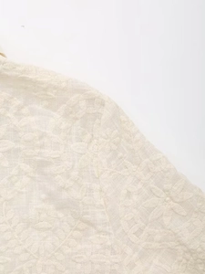 Gros plan détaillé de la broderie florale blanche et des détails ajourés sur tissu coton
