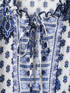 Detail view of V-neckline with ties and ruffle trim on blue paisley print dress