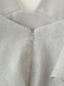 Detail of invisible teardrop zipper on silver metallic beaded mini dress fabric