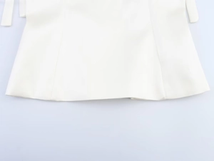 Detailed view of white ribbon straps and hem on a minimalist spring bow camisole top